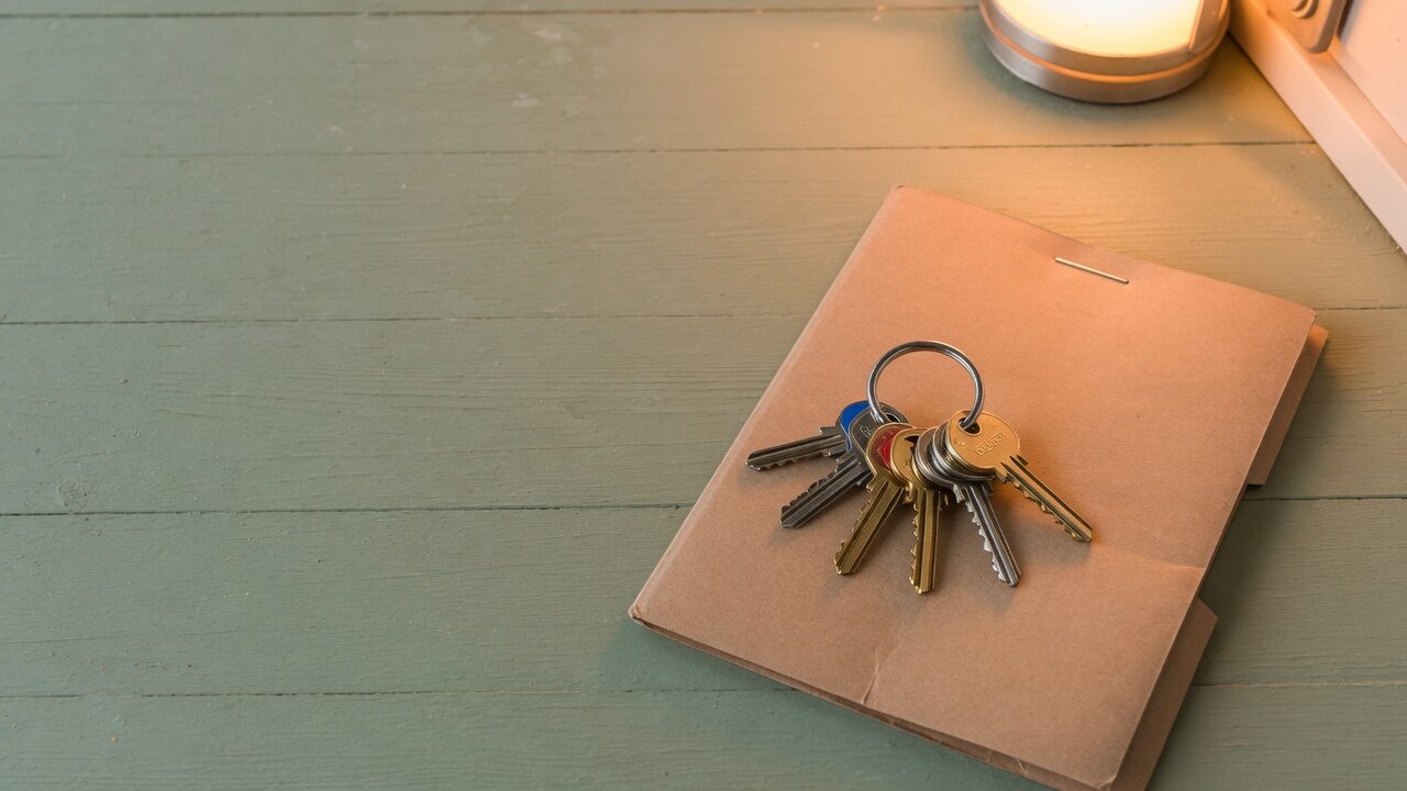 New house keys resting on a closing document folder
